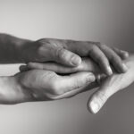 One hand holding another hand in support