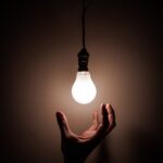 hand reaching for a light bulb as a metaphor for reaching for inspiration